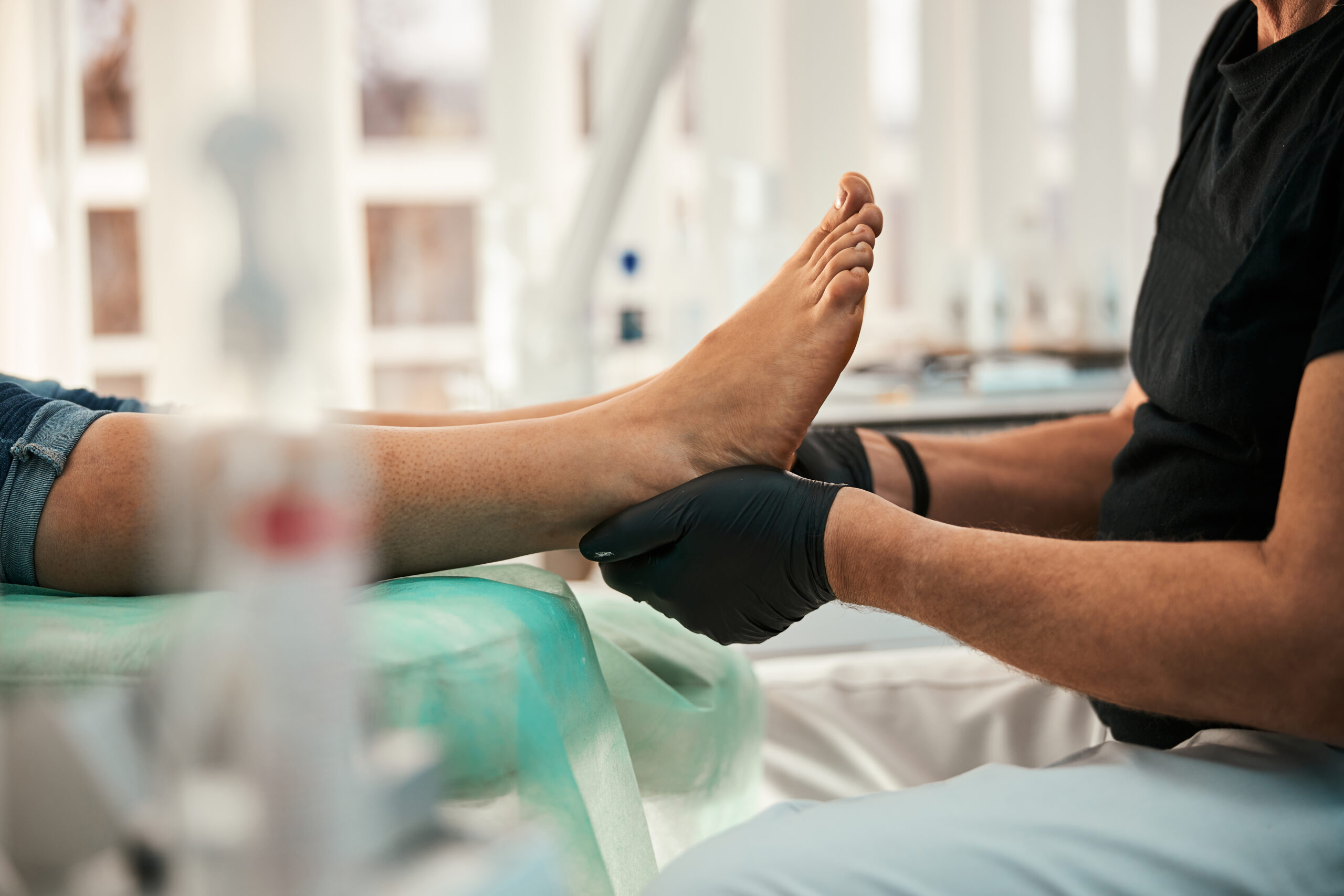 Professional podiatrist sitting in semi position while doing medical treating procedure for patient